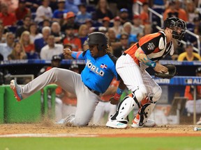 Vladimir Guerrero Jr. of the Toronto Blue Jays and the World Team slides past Zack Collins #8 of the Chicago White Sox and the U.S. Team to score in the seventh inning on a single by Tomas Nido #7 of the New York Mets and the World Team during the SiriusXM All-Star Futures Game at Marlins Park on July 9, 2017 in Miami, Florida.