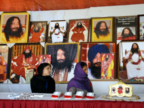 Indian followers of deceased guru Ashutosh Maharaj sitting in front of posters bearing his image at a stall during a congregation at his ashram.
