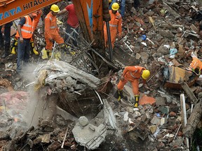 Indian rescue workers and fire officials look for survivors in debris at the site of a building collapse  in Mumbai on July 25, 2017. Rescuers were frantically searching for up to 40 people feared trapped in a four-storey building that collapsed July 25 in India's financial capital of Mumbai, officials said.