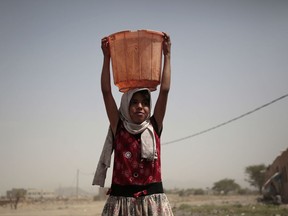 A girl carries a bucket filled with water from a well that is allegedly contaminated with cholera bacteria, on the outskirts of Sanaa, Yemen, Wednesday, July 12, 2017. The U.N. health agency said Tuesday that plans to ship cholera vaccine to Yemen are likely to be shelved over security, access and logistical challenges in the war-torn country. Yemen's suspected cholera caseload has surged past 313,000, causing over 1,700 deaths in the world's largest outbreak. (AP Photo/Hani Mohammed)