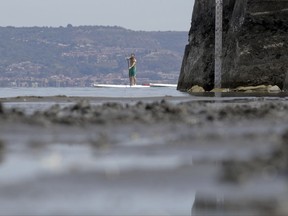 A man paddles by a water gauge in Lake Bracciano, about 35 kilometers northwest of Rome, Thursday, July 27, 2017. Rome area's governor last week ordered no more water drawn from Lake Bracciano, which supplies much of the Italian capital, raising risk for staggered water supply shutdowns as long as eight hours daily in alternating neighborhoods. Scarce rain and chronically leaky aqueducts have combined this summer to hurt farmers in much of Italy and put Romans at risk for drastic water rationing starting later this week.  (AP Photo/Andrew Medichini)