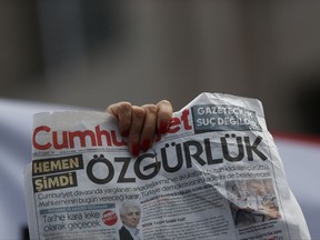 An activist holds a copy of the Cumhuriyet paper outside the court in Istanbul, Friday, July 28, 2017, protesting against the trial of journalists and staff from the newspaper, staunchly opposed to President Recep Tayyip Erdogan, who are accused of aiding terror organisations. The court was expected to decide whether the suspects should be released from jail pending the trial's outcome. The headline reads: " Freedom." (AP Photo/Emrah Gurel)