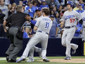 Los Angeles Dodgers manager Dave Roberts, center, is held back by third baseman Logan Forsythe (11) and home plate umpire Greg Gibson, left as the Dodgers and the San Diego Padres come onto the field during an argument in the second inning of a baseball game Friday, June 30, 2017, in San Diego.  Dodgers' Alex Wood is at right. (AP Photo/Gregory Bull)