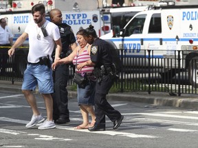 Police help people cross the street outside the Bronx Lebanon Hospital in New York after a gunman opened fire there on Friday, June 30, 2017. The gunman, identified as Dr. Henry Bello who used to work at the hospital, returned with a rifle hidden under his white lab coat, law enforcement officials said. (AP Photo/Mary Altaffer)