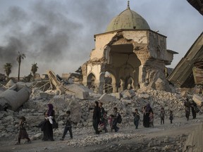 Fleeing Iraqi civilians walk past the heavily damaged al-Nuri mosque as Iraqi forces continue their advance against Islamic State militants in the Old City of Mosul, Iraq, Tuesday, July 4, 2017. As Iraqi forces continued to advance on the last few hundred square kilometers of Mosul held by the Islamic State group, the country's Prime Minister said Tuesday the gains show Iraqis reject terrorism. (AP Photo/Felipe Dana)