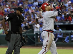 Home plate umpire Alan Porter, left, watches as Los Angeles Angels' Yunel Escobar crosses the plate celebrating his solo home run against the Texas Rangers in the second inning of a baseball game, Saturday, July 8, 2017, in Arlington, Texas. (AP Photo/Tony Gutierrez)