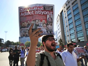 Activists, one holding today's copy of the Cumhuriyet newspaper, march to the court in Istanbul, Monday, July 24, 2017, protesting against a trial of journalists and staff from the newspaper, accused of aiding terror organizations. The newspaper headline reads in Turkish: "We want justice." Journalists and staff from a Turkish newspaper staunchly opposed to President Recep Tayyip Erdogan are going on trial in Istanbul, accused of aiding terror organizations -- a case that has added to concerns over rights and freedoms in Turkey. (AP Photo/Lefteris Pitarakis)