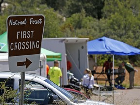 First responders gather near the entrance to the First Crossing recreation area during the search and rescue operation for a victim in a flash flood along the banks of the East Verde River Monday, July 17, 2017, in Payson, Ariz. The bodies of nearly a dozen children and adults have been found after Saturday's flash flooding poured over a popular swimming area in the Tonto National Forest. (AP Photo/Ross D. Franklin)