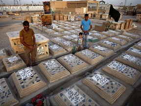 In this Wednesday, July 19, 2017 photo, men pray at a cemetery for Shiite Volunteers fighters killed fighting with Islamic State group militants in the Wadi al-Salam, or "Valley of Peace" cemetery in Najaf, 100 miles (160 kilometers) south of Baghdad, Iraq. Iraq's political, religious and military leaders are debating the future of the country's powerful Shiite militias after defeating the Islamic State group in Mosul. (AP Photo/Anmar Khalil)