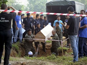 FILE - In this Monday, June 22, 2015, file photo, Malaysian police carry a coffin containing the remains of a Rohingya migrant for a mass burial ceremony in Kedah, Malaysia. A Thai court, Wednesday, is issuing rulings in a major human trafficking trial with more than 103 defendants, including a senior army officer, who were arrested in 2015 after 36 bodies were discovered in shallow graves in southern Thailand. (AP Photo/Gary Chuah, File)