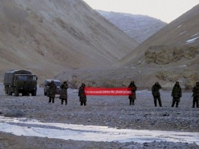 FILE - In this Sunday, May 5, 2013, file photo, Chinese troops hold a banner which reads "You've crossed the border, please go back" in Ladakh, India. India says it is ready to hold talks with China with both sides pulling back their forces to end a standoff along a disputed territory high in the Himalayan mountains. (AP Photo, File)