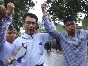 In this image made from video released by the Democratic Voice of Burma, left to right, Burmese journalists La Wei, from the Irrawaddy, Aye Nai, from the Democratic Voice of Burma, and Pyi Phone Aung, from the Democratic Voice of Burma raise their chained wrists decrying the lack of freedom and democracy as they leave the court after facing charges of unlawful association, Tuesday, July 18, 2017, in Hsipaw, Shan state, Myanmar. The video was recorded Tuesday, and it underscores just how little has changed in this Southeast Asian country since former Nobel Laureate and longtime opposition leader Aung San Suu Kyi won elections last year. (Democratic Voice of Burma via AP)