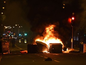 A fire roadblock is made during a protest on a main street in London, late Friday, July 28, 2017. Protesters angry over the death of a young black man following a police chase have clashed with riot police in London, throwing bottles and fireworks and setting garbage cans on fire. (Lauren Hurley/PA Wire via AP)