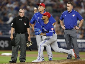 From left, home plate umpire Jerry Meals, Toronto Blue Jays manager John Gibbons and Blue Jays trainer, Mike Frostad, right, watch as Toronto Blue Jays starting pitcher Marcus Stroman (6) throws under supervision during the fifth inning of a baseball game against the New York Yankees in New York, Monday, July 3, 2017.