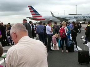 In this image taken from video, passengers stand on the tarmac after being evacuated at Manchester Airport, England, Wednesday July 5, 2017. Manchester Airport says a terminal has been evacuated while authorities investigate a suspicious bag. (AP Photo)