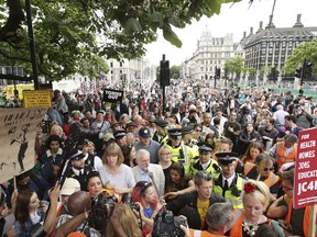 A Saturday July 1, 2017 photo of Labour Party leader Jeremy Corbyn, centre in white jacket, being mobbed by the crowd after addressing an anti-austerity rally in Parliament Square, London, following a march through the city as part of an anti-austerity protest. Corbyn made emergency services the focus of the march on Parliament Saturday when demonstrators called for an end to the 1 percent cap on pay increases for public employees. With the inflation rate now at 2.9 percent, the cap means the spending power of government workers is shrinking. (Yui Mok/PA via AP)