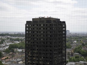 Emergency workers walk on the roof of the fire-gutted Grenfell Tower in London, after a fire engulfed the 24-storey building. British authorities say they won't prosecute anyone who unlawfully sublet apartments in the west London tower block before it was devastated by fire