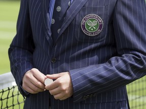 A referee prepares to toss a coin for Italy's Simone Bolelli against Taiwan's Yen-Hsun Lu on the opening day at the Wimbledon Tennis Championships in London Monday, July 3, 2017. (AP Photo/Tim Ireland)