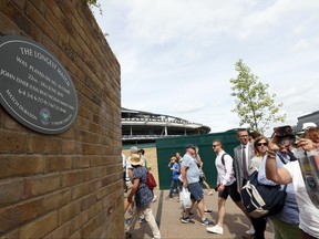 In this photo taken on Tuesday, July 4, 2017, people photograph a plaque at the Wimbledon Tennis Championships in London. And the All England Club insists there is a very simple explanation for why the marker posted on a brick wall outside Court 18 - noting it was the site of John Isner's record-breaking 70-68 fifth-set victory over Nicolas Mahut in 2010 - was missing for a bit. (AP Photo/Kirsty Wigglesworth)