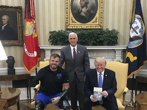 In this photo provided by the Travis Mills Foundation, Travis Mills, left, poses with President Donald Trump and Vice President Mike Pence in the Oval Office at the White House in Washington. Mills, an Army veteran who lost all four limbs in an explosion in Afghanistan, opened a retreat in Rome, Maine, in June for other injured veterans. Mills said he was meeting with with the vice president about his veterans retreat when he got a chance to meet the president, too. (Travis Mills Foundation via AP)