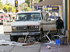An official looks into a van that plowed into a group of people on a Los Angeles sidewalk on Sunday, July 30, 2017. A witness to the crash told The Associated Press the van jumped a curb and careened into a group of people eating outside The Fish Spot restaurant in the city's Mid-Wilshire neighborhood. The cause of the crash is under investigation. (AP Photo/Damian Dovarganes)