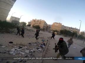 FILE - This photo posted on a file sharing website Wednesday, Jan. 11, 2017, by the Islamic State Group in Sinai, a militant organization, shows a deadly attack by militants on an Egyptian police checkpoint, in el-Arish, north Sinai, Egypt. The officials say the Friday, July 7, 2017 attack started when a suicide car bomber rammed his vehicle into the checkpoint in southern Rafah village of el-Barth, followed by heavy shooting by dozens of masked militants on foot. Arabic reads, "The advance of the squad to kill any apostates left alive." (Islamic State Group in Sinai via AP, File )