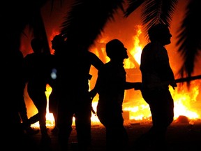 FILE - In this Friday, Sept. 21, 2012 file photo, Libyan civilians watch fires at an Ansar al-Shariah Brigades compound, after hundreds of Libyans, Libyan Military, and Police raided the Brigades base, in Benghazi, Libya. Factions of the group in 2014 pledged allegiance to the Islamic State group. Military victories over extremist groups along Libya's Mediterranean coastline has forced hundreds of militants, including Islamic State fighters, to seek refuge in the vast deserts of the North African nation, already home to militias, criminal gangs and mercenaries. The area provides a sanctuary for militants to reorganize, recruit and plot a potential comeback as the Islamic State group loses ground.(AP Photo, File)