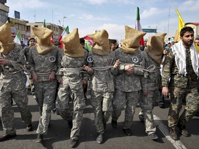 FILE - In this Feb. 11, 2016 file photo, members of the Iranian Basij paramilitary force reenact the January 2016 capture of U.S sailors by the Revolutionary Guard in the Persian Gulf, in a rally commemorating the 37th anniversary of Islamic Revolution, in Tehran, Iran. Mohsen Dehnavi, an Iranian cancer researcher who was denied entry to the U.S. previously headed a student branch of a volunteer paramilitary militia, footage aired on state television Thursday, July 13, 2017, showed. In comments to the channel at the Tehran airport, he defended his travel to the United States as solely intended for science and research. (AP Photo/Ebrahim Noroozi, File)