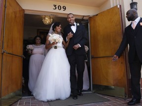 Two-time Olympic jumper Jamie Nieto, center right, and his bride Shevon Stoddart, a Jamaican hurdler, walks out of a church after their wedding ceremony Saturday, July 22, 2017, in El Cajon, Calif. Step by halting step, Nieto made good on his vow to walk his new wife down the aisle of the church and out the door to a waiting limousine. It was roughly 130 steps, with a stop about halfway down the aisle for a kiss to appease the photographers. No cane, no walker, just his right arm holding onto his wife's left arm. (AP Photo/Jae C. Hong)