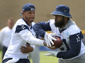 Dallas Cowboys quarterback Dak Prescott, left, hands off to running back Ezekiel Elliott during practice at the NFL football team's training camp in Oxnard, Calif., Monday, July 24, 2017. (AP Photo/Michael Owen Baker)