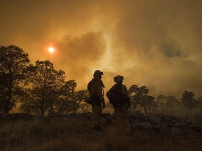 CalFire firefighter Jake Hainey, left, and engineer Anna Mathiasen watch as a wildfire burns near Oroville, Calif., on Saturday, July 8, 2017. The fast-moving wildfire in the Sierra Nevada foothills destroyed structures, including homes, and led to several minor injuries, fire officials said Saturday as blazes threatened homes around California during a heat wave. (AP Photo/Noah Berger)