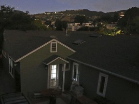 The Pacific Palisades area of Los Angeles at twilight is blacked out, the only light coming from a laptop computer screen in a home, foreground, and from a few others with backup power, as the Los Angeles Department of Water and Power said about 140,000 people are without electricity after the agency shut down a power station in the northeast San Fernando Valley that caught fire Saturday, July 8, 2017. (AP Photo/Reed Saxon)