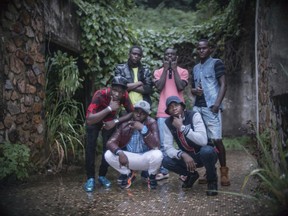 In this photo taken Tuesday June 27, 2017, Lionel Fotot, wearing a brown leather jacket and white pants, poses for a photograph with other members of the One Force Hip Hop band in Bangui, Central African Republic. Fotot once watched a crowd kill a 6-year-old Muslim boy with a machete. He can't shake the memories of the brutalities he witnessed as Central African Republic collapsed into sectarian violence. So the young hip hop artist was heartened when his One Force group, comprised of Christians and Muslims, performed to a packed crowd at the largest venue in the capital, the 20,000-seat Barthelemy Boganda Stadium. (AP Photo/Zack Baddorf)
