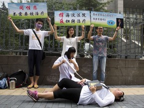 FILE - In this July 31, 2014 file photo, gay rights campaigners act out electric shock treatment to protest outside a court when the first court case in China involving so-called conversion therapy is held in Beijing, China. A gay man in central China has successfully sued a mental hospital over forced conversion therapy on June 26, 2017, in what activists are hailing as the first such victory in the country where the LGBT rights movement is gradually emerging form the fringes. (AP Photo/Ng Han Guan, File)