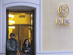 FILE - In this Wednesday, Feb. 17, 2016, file photo, a woman walks past a Spanish Civil Guard policeman as she leaves an Industrial and Commercial Bank of China, or ICBC, branch in Madrid, Spain. In February, Spain arrested six executives from China's largest bank, the Industrial and Commercial Bank of China, accusing them of facilitating a Chinese money-laundering network that sold its services to Spanish and Chinese criminal syndicates in Europe, according to Europol, which also is investigating the network's links to France, Germany and Lithuania. (AP Photo/Francisco Seco, File) ORG XMIT: BKCD403