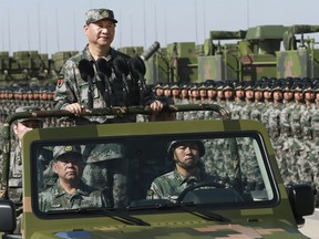 In this photo released by Xinhua News Agency, Chinese President Xi Jinping stands on a military jeep as he inspects troops of the People's Liberation Army during a military parade