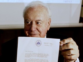 FILE - In this November 7, 2005 file photo, former Australian Prime Minister Gough Whitlam holds up the original copy of his dismissal letter he received from then Governor General Sir John Kerr on the 11th of November 1975 at a book launch in Sydney, Australia. Historian, Professor Jenny Hocking, is going to court in July, 2017 in an attempt to force Australian authorities to release secret letters that would reveal what Queen Elizabeth II knew of her representative's shocking scheme to dismiss Australia's government more than 40 years ago. (AP Photo/Mark Baker, File)