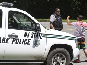 New Jersey State Park police block the entrance to Bulls Island state recreation area during the state government shutdown in Stockton, N.J. , Sunday, July 2, 2017. New Jersey's government shutdown dragged into a second day Sunday without a resolution to the stalemate between a defiant Republican Gov. Chris Christie and an unmoving Democratic Assembly Speaker Vincent Prieto. (Ed Murray/NJ Advance Media via AP)