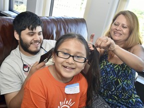 In this Wednesday, July 19, 2017 photo, Norwalk resident Nury Chavarria straightens out her nine-year-old daughter Hayley Chavarria's pigtails as her oldest son, Elvin Martinez, 21 gets in on the fun before a press conference in New Haven, Conn.  U.S. immigration officials said Friday, July 21, 2017,  they consider Chavarria, who is trying to avoid deportation by seeking sanctuary in a Connecticut church, to be a fugitive, but acknowledge they have a policy that restricts them from entering a house of worship except in extraordinary circumstances. Connecticut Gov. Dannel P. Malloy, said the attempt to deport the housekeeper and mother of four shows President Donald Trump's administration is not being truthful when it says its immigration policies are focused on "the bad guys." (Catherine Avalone/New Haven Register via AP)