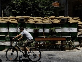 A man passes with his bicycle by a wall with barrels and sand bags that block a road to the Turkish Cypriots breakaway north part between the U.N buffer zone that divided the Greek and Turkish Cypriots controlled areas in central divided capital Nicosia, Cyprus, Friday, June 30, 2017. U.N. Secretary-General Antonio Guterres has joined high-level talks aimed at reunifying ethnically divided Cyprus amid hopes he can help nudge rival sides toward a breakthrough. Two days of talks at the Swiss resort of Crans-Montana have made no real progress on the core issue of the island's future security that could unlock an overall peace accord. (AP Photo/Petros Karadjias)