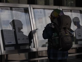 A woman, who did not wish to give her name, reads newspaper front pages displayed at the Newseum in Washington, Monday, July 10, 2017. News outlets are seeking permission from Congress for the right to negotiate jointly with Google and Facebook, two companies that dominate online advertising and online news traffic. (AP Photo/Carolyn Kaster)