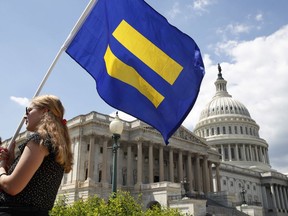 A supporter of LGBT rights holds up an "equality flag" on Capitol Hill in Washington, Wednesday, July 26, 2017, during an event held by Rep. Joe Kennedy, D-Mass. in support of transgender members of the, in response to President Donald Trump's declaration that he wants transgender people barred from serving in the U.S. military "in any capacity," citing "tremendous medical costs and disruption." (AP Photo/Jacquelyn Martin)