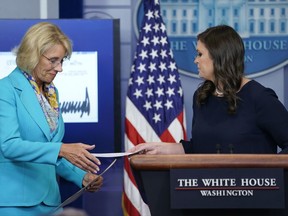 White House press secretary Sarah Huckabee Sanders, right, hands Education Secretary Betsy DeVos a check signed by President Donald Trump in the Brady Press Briefing room of the White House in Washington, Wednesday, July 26, 2017. President Trump to donate his second quarter salary to the Education Department. (AP Photo/Pablo Martinez Monsivais)