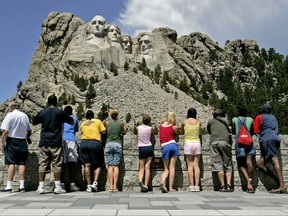 FILE - In this July 21, 2005 file photo, visitors watch while workers pressure wash the granite faces of George Washington, left, Thomas Jefferson, Theodore Roosevelt and Abraham Lincoln at Mount Rushmore National Memorial in South Dakota. The Democracy Index, compiled by the London-based Economist Intelligence Unit, ranked the U.S. at 21st worldwide in 2016, tied with Italy and trailing Norway, Canada and Uruguay, among others. While Norway and several other Scandinavian countries are considered "full democracies," according to the index, the U.S. last year fell to "flawed democracy," receiving low scores for "functioning of government" and "political participation." (AP Photo/Charlie Riedel, File)