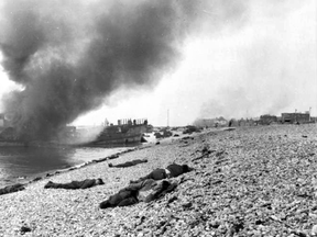 Destroyed landing craft on fire with Canadian dead on the beach following the Dieppe raid.