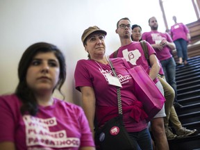 Planned Parenthood supporters listen as the Sergeant At Arms for Texas Senate tells the activists that they are not allowed to enter the secure back hallway of the Senate while they are in session at the State Capitol