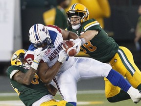 Montreal Alouettes' Nik Lewis is tackled by Edmonton Eskimos' Adam Konar (38) and Garry Peters (34) during second half CFL action in Edmonton on Friday, June 30, 2017.