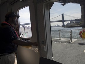 In this Friday, June 30, 2017 photo, deckhand Pierce Collazo looks out to the Dumbo stop as the South Brooklyn route NYC Ferry prepares to dock in the Brooklyn borough of New York. New York City's new fleet of high-tech ferries is putting out the call for deckhands. No maritime experience necessary, only a high-school diploma, people skills and ambition for advancement. (AP Photo/Mary Altaffer)