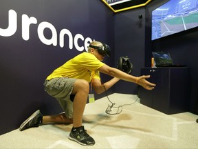 In this Friday, July 7, 2017, photo, Dennis Milman reaches to catch a virtual ball at the All-Star FanFest in Miami Beach, Fla. Virtual Reality baseball is a hit at the All-Star FanFest in Miami. Fans get to feel what it's like to be the San Francisco Giants' Buster Posey catching without the pain of snatching major league pitches at 86-to-93 mph. (AP Photo/Alan Diaz)