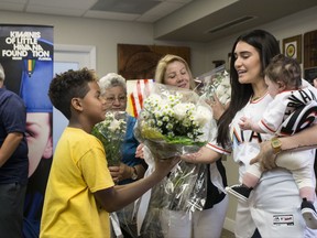 Antoniel Ruiz, 11, gives flowers to Maria Arias in part of the commemoration of José Fernández at Kiwanis of Little Havana in Miami on Monday, July 31, 2017. (Sebastián Ballestas/Miami Herald via AP)